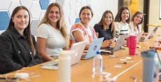 A group of UNE women business students sits around a conference table